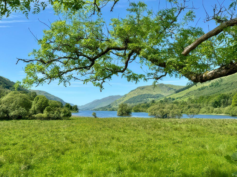 A scenic view of a lake surrounded by mountains and trees at Culearn Mill, Balquhidder, Perthshire, Scotland