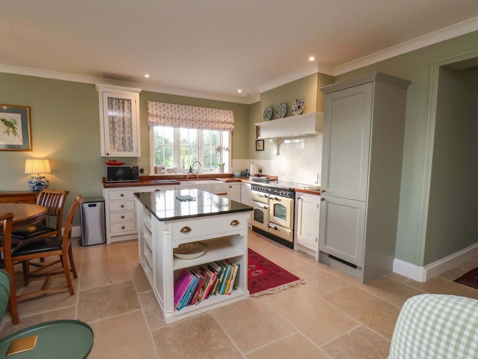 A kitchen with an island, stove, and seating area at Roding Cottage in Egton