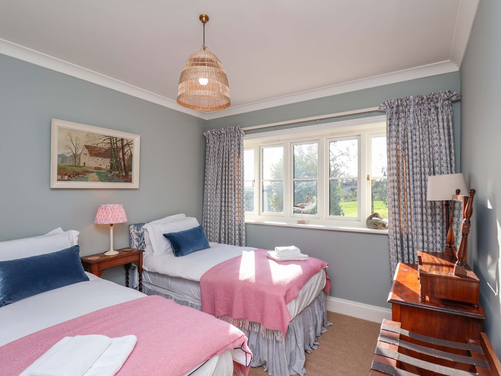 A bedroom with two beds and a painting at Roding Cottage in Egton
