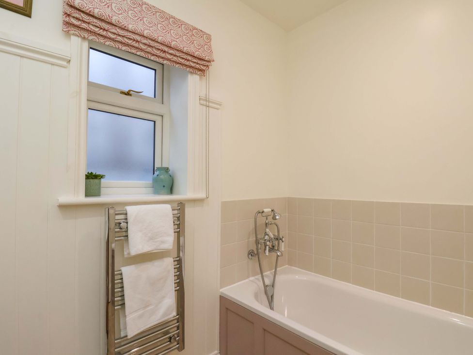 A bathroom with a bathtub and towel rack at Roding Cottage in Egton