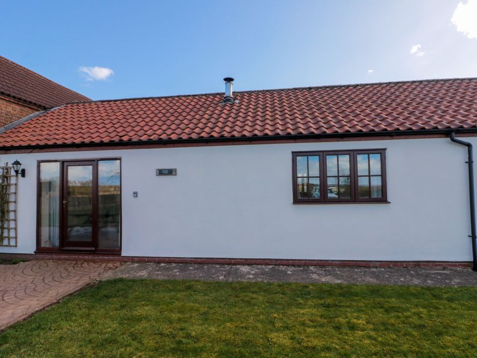A single story building with white walls red tiled roof and grass in front at Partridge Cottage neaer Filey