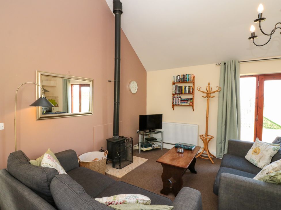 A living room with two sofas a wood stove a coffee table and a TV at Partridge Cottage neaer Filey