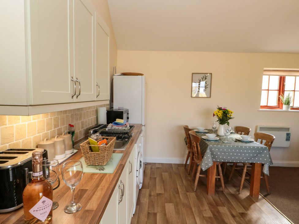 A kitchen with countertop appliances and a dining table set for six at Partridge Cottage neaer Filey