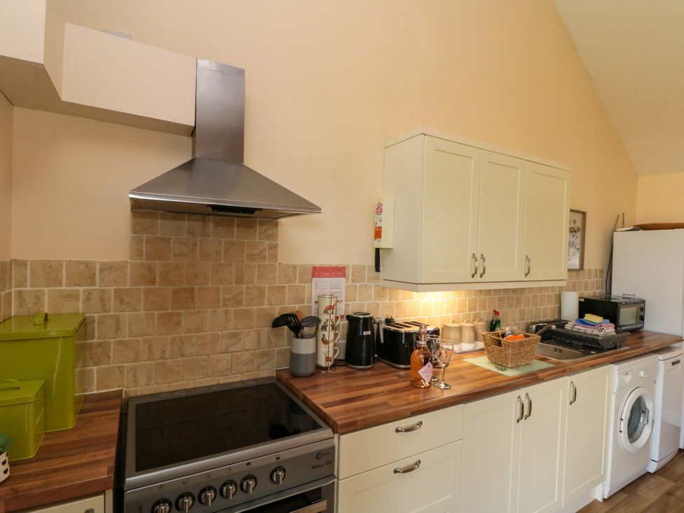 A kitchen with stove and oven range hood coffee machines toaster and washing machine at Partridge Cottage neaer Filey