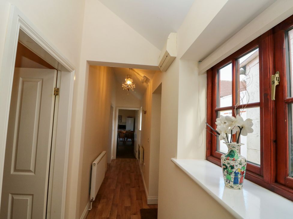 Hallway with wooden floor radiator chandelier and vase on windowsill at Partridge Cottage neaer Filey