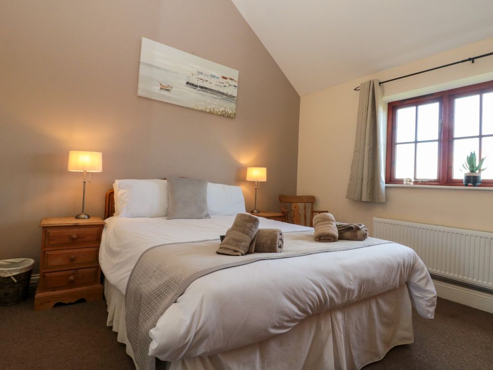 A bedroom with a bed and bedside tables with lamps near a window at Partridge Cottage neaer Filey