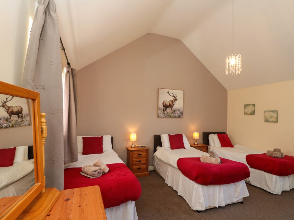 A bedroom with three single beds with red blankets and pillows at Partridge Cottage neaer Filey