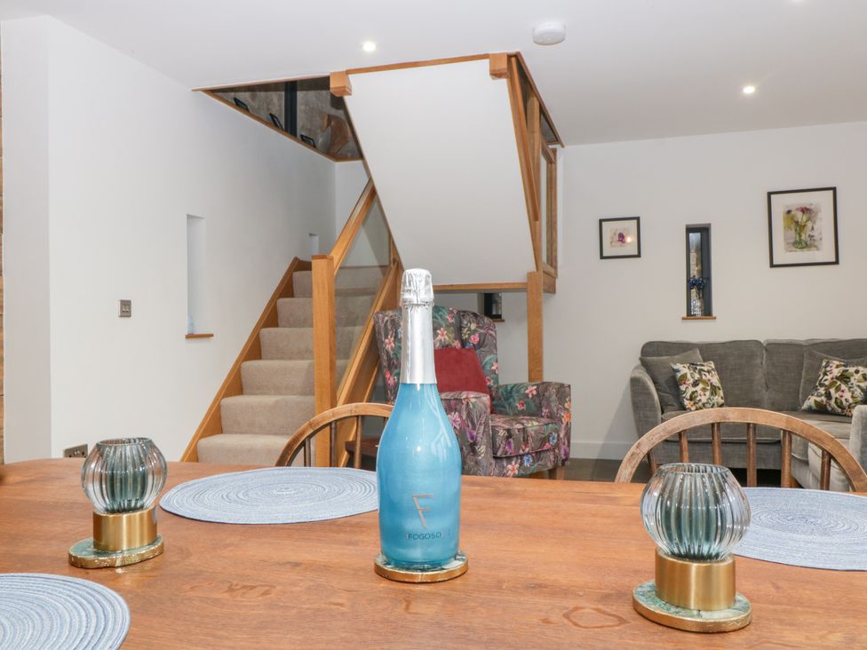 A living room with a staircase and dining table at The Hay Barn in Huntley