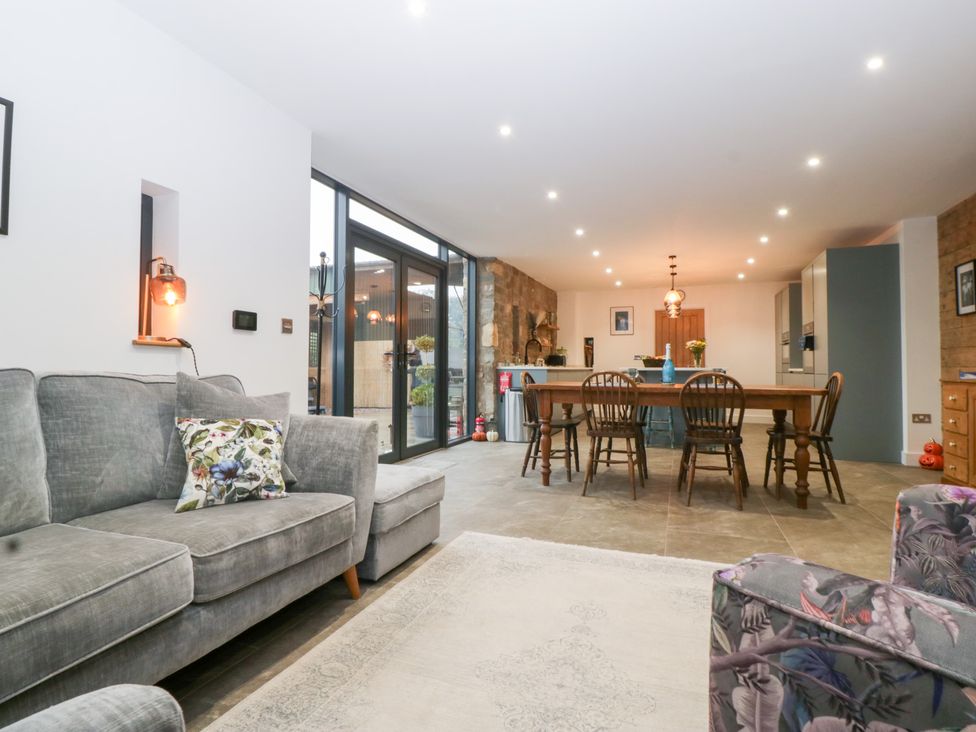 A living room with a sofa and dining area at The Hay Barn in Huntley