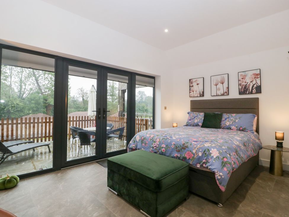 A bedroom with a bed and sliding doors at The Hay Barn in Huntley