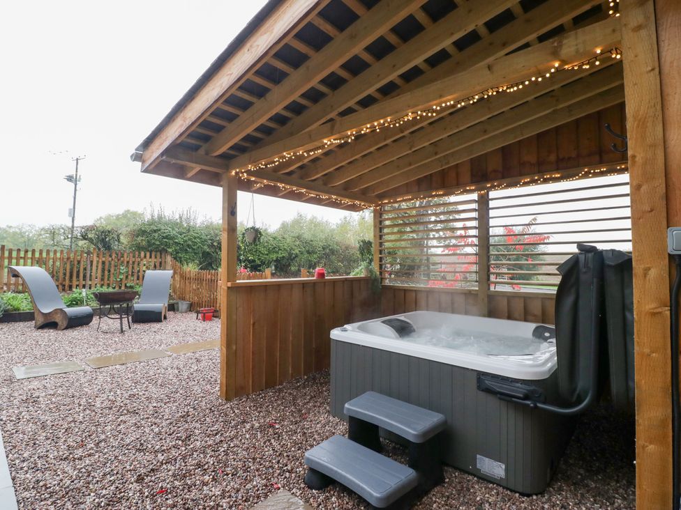 An outdoor area with a hot tub and seating at The Hay Barn in Huntley