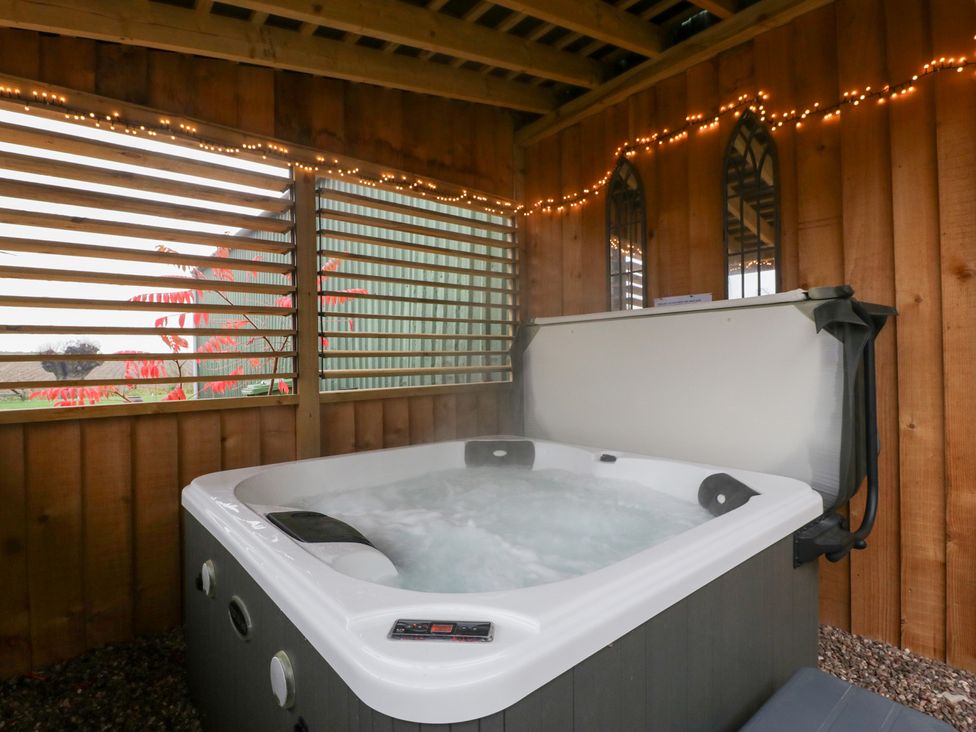 A hot tub in a wooden structure with lights at The Hay Barn in Huntley