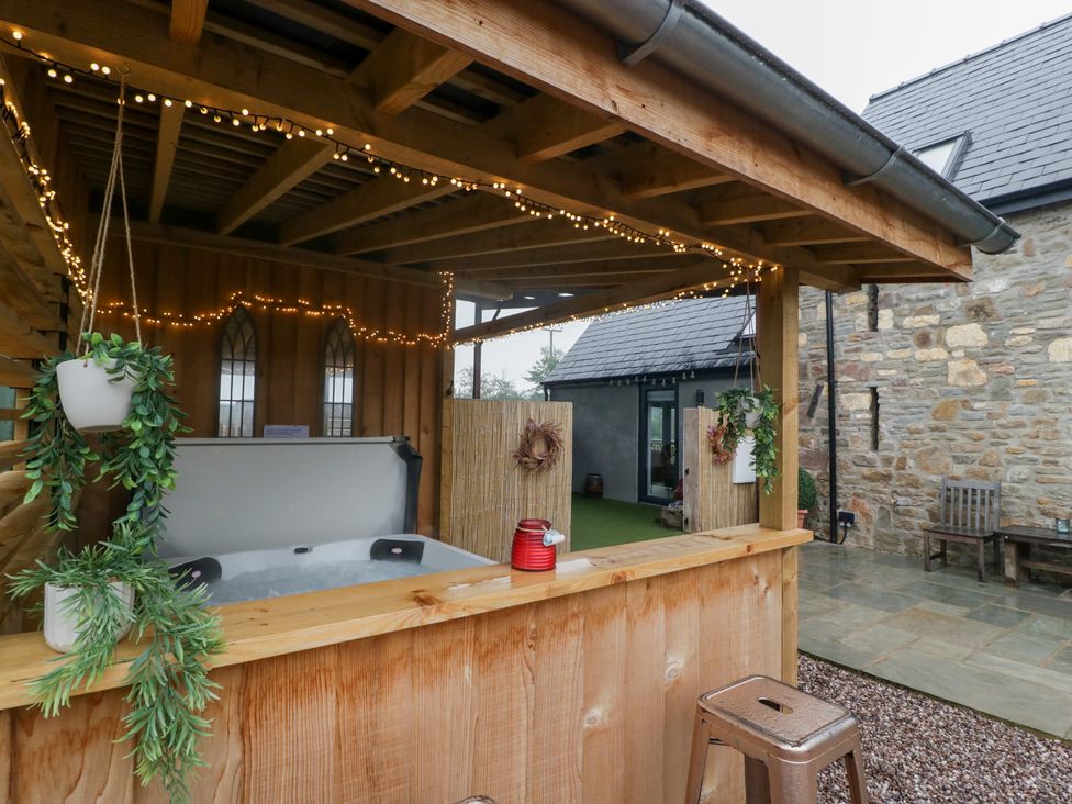 An outdoor area with a hot tub and wooden structure at The Hay Barn in Huntley