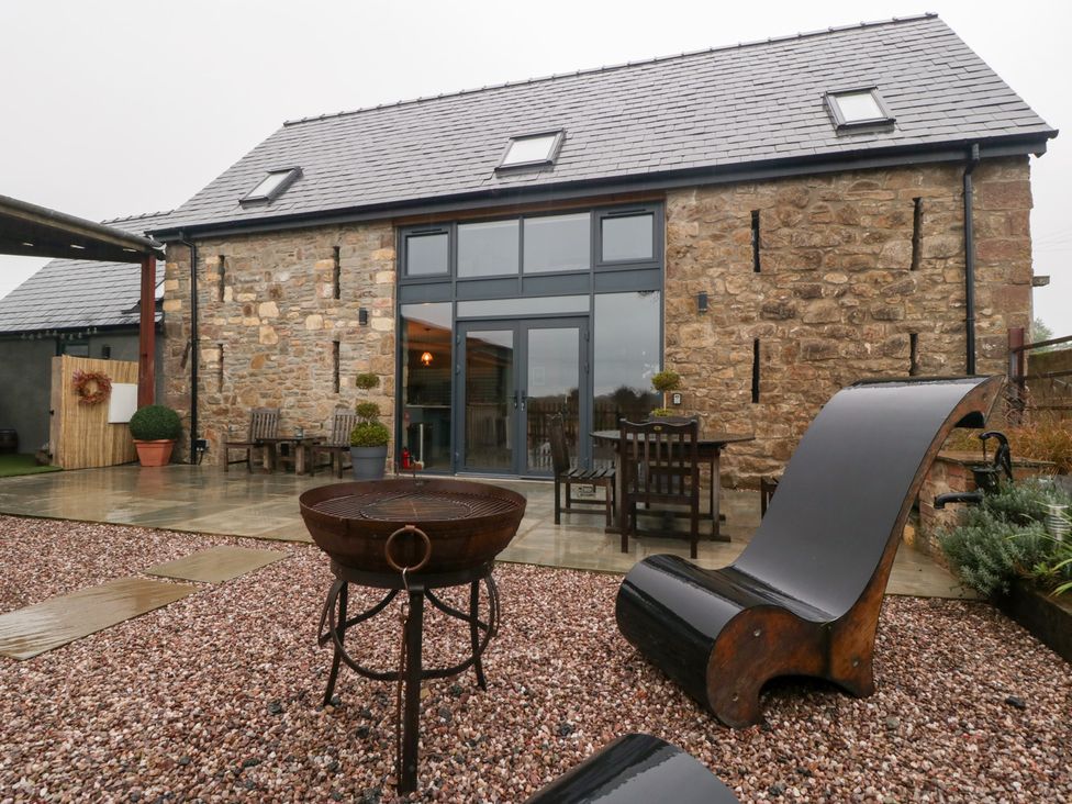 An outdoor area with a stone building and furniture at The Hay Barn in Huntley