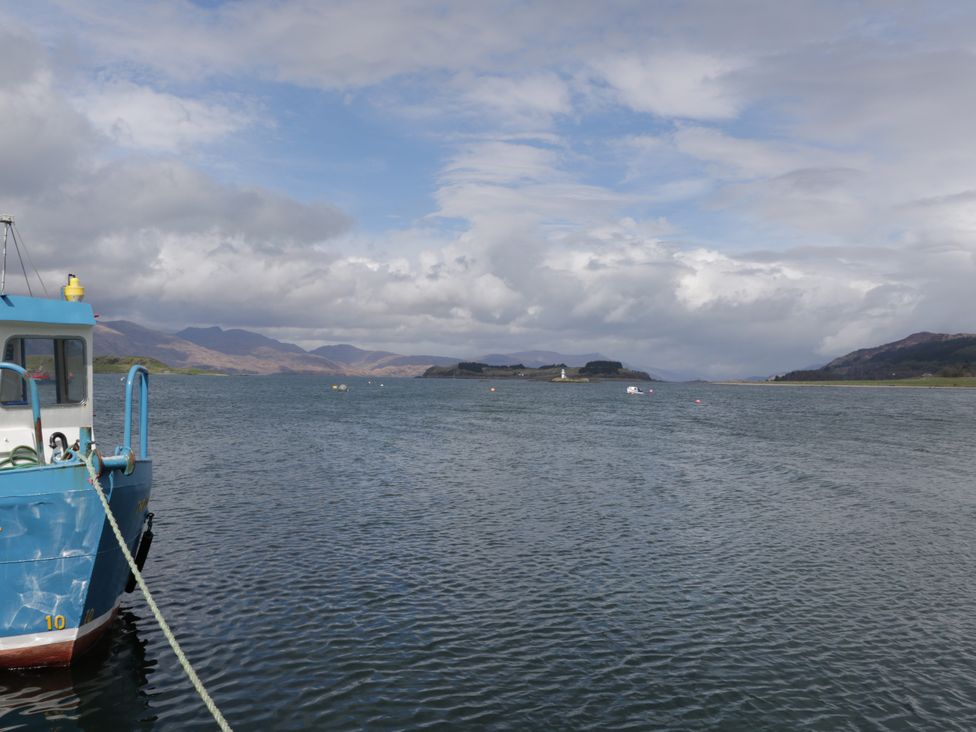 A boat on water with mountains and clouds at Tirlaggan Úr in Lismore