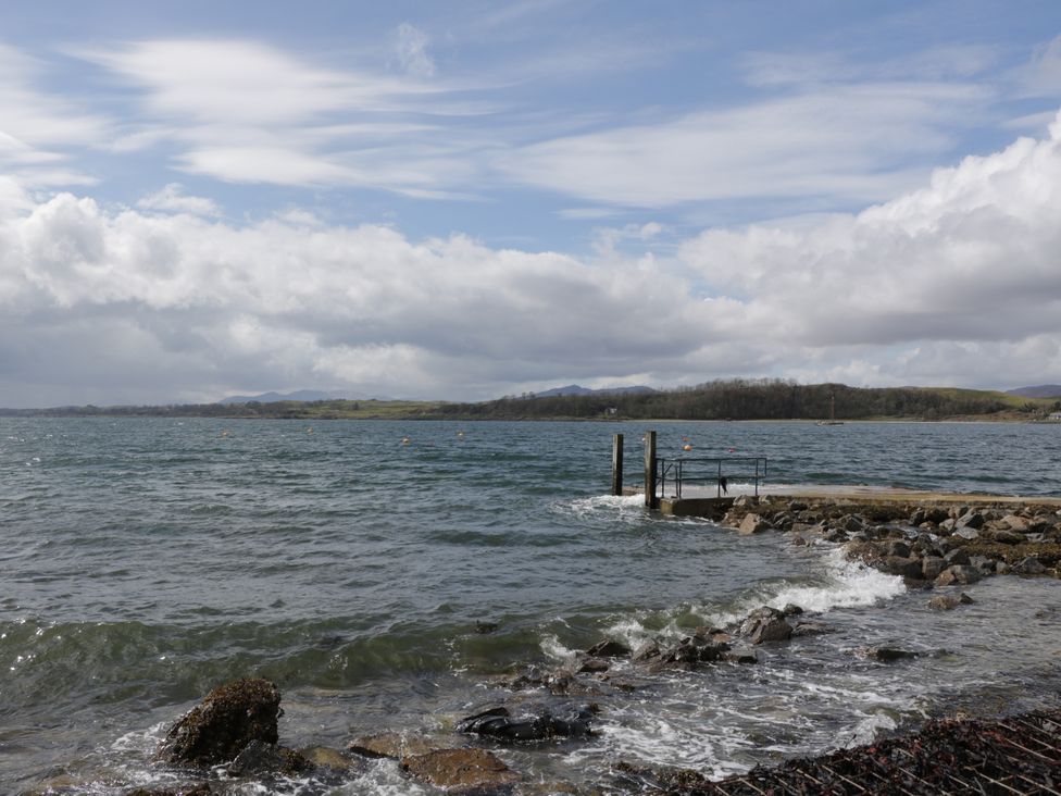 A view of water with a pier and rocky shore at Tirlaggan Úr in Lismore
