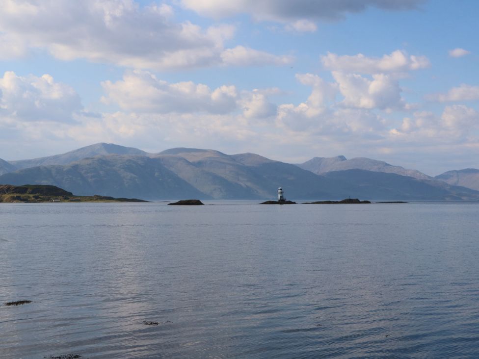 A landscape view with a lighthouse on an island and mountains in the background at Tirlaggan Úr in Lismore