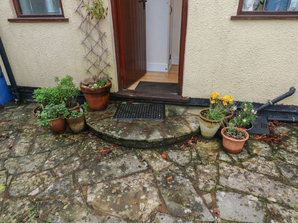 An entrance with flower pots and a doormat at Bridge Cottage in Budleigh Salterton