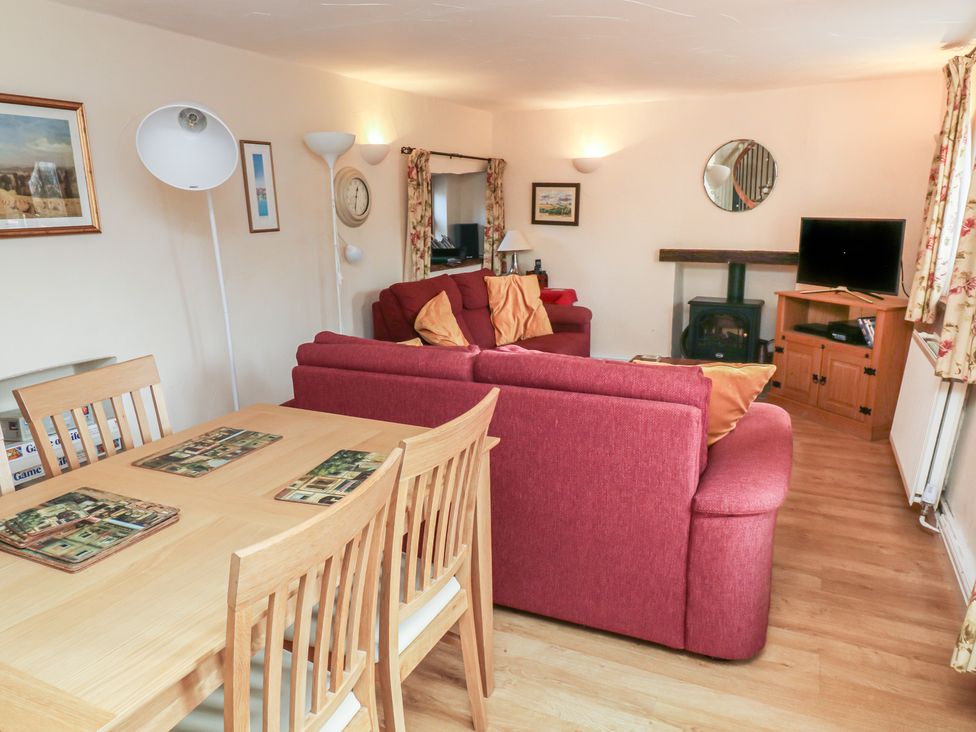 A living room with a sofa, table, and television at Bridge Cottage Budleigh Salterton