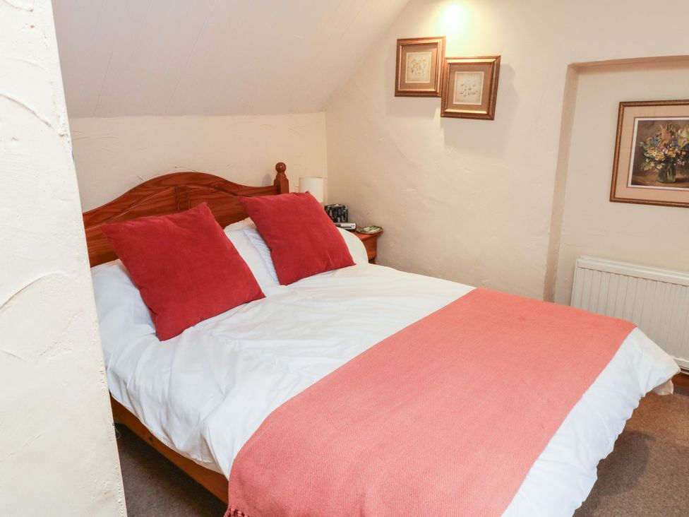 A bedroom with a bed and framed pictures at Bridge Cottage in Budleigh Salterton
