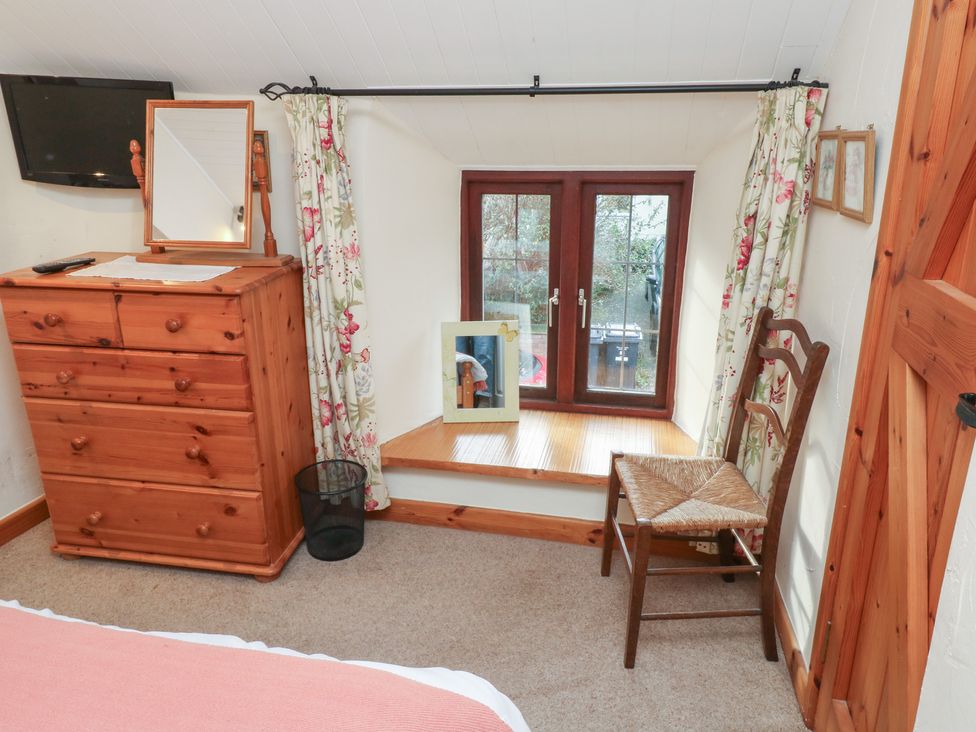 A bedroom with a dresser and a chair at Bridge Cottage Budleigh Salterton