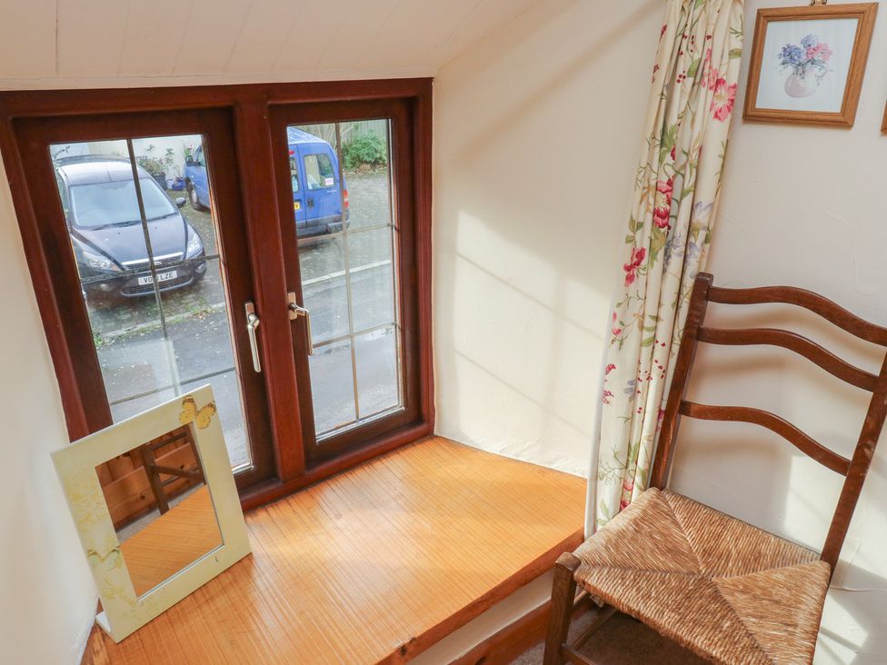 A corner nook with a window, chair, and mirror at Bridge Cottage Budleigh Salterton