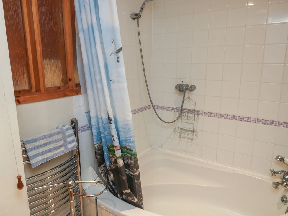 A bathroom with a bathtub and shower at Bridge Cottage in Budleigh Salterton
