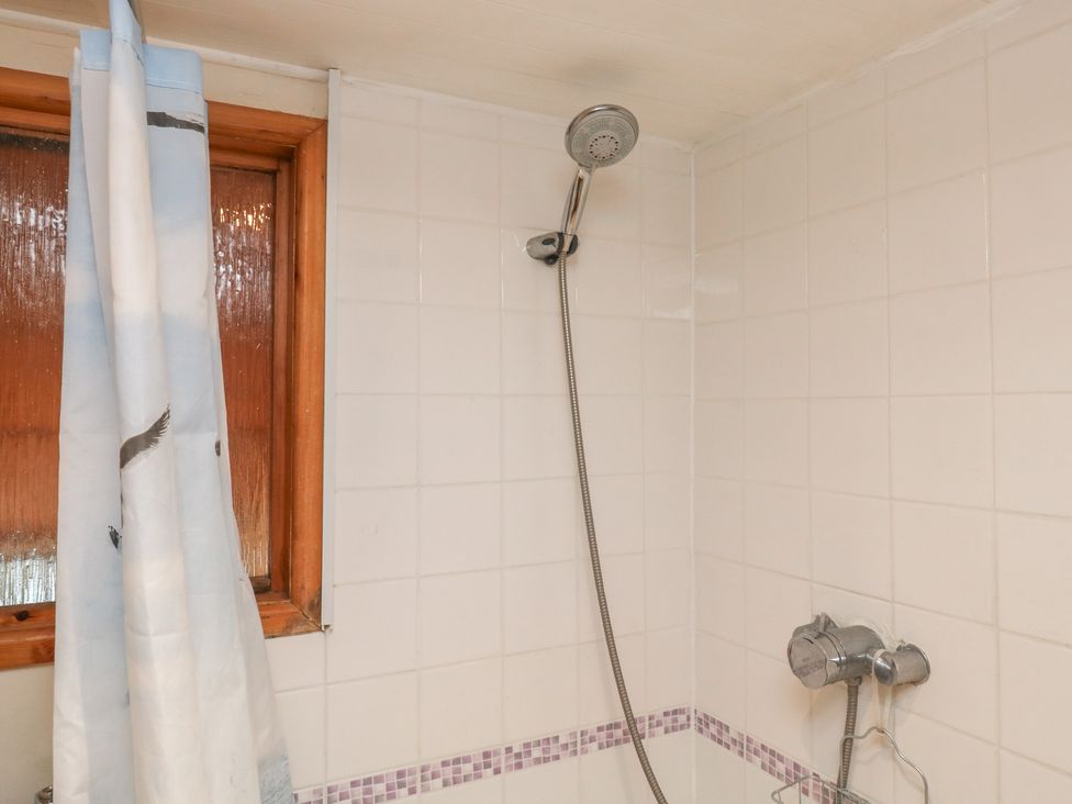 A shower with a curtain and window in the bathroom at Bridge Cottage Budleigh Salterton
