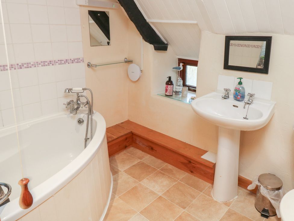 A bathroom with a bath tub and sink at Bridge Cottage in Budleigh Salterton