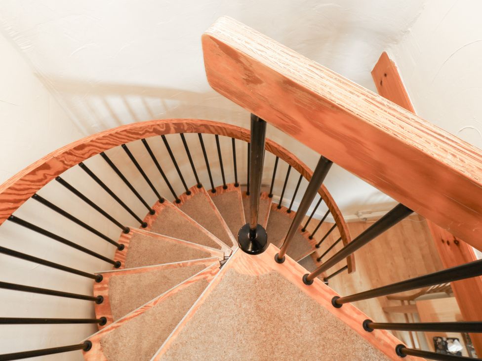 A spiral staircase with wooden handrail and metal railing at Bridge Cottage Budleigh Salterton