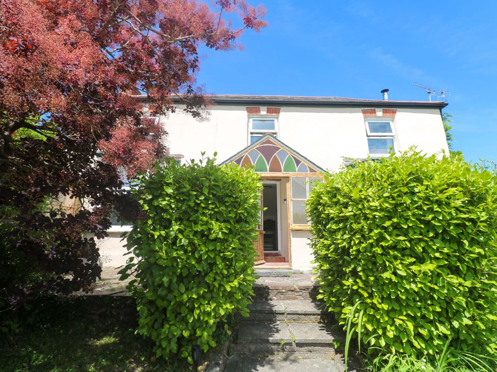 A house entrance with a pathway surrounded by hedges at Greenways in Perranporth