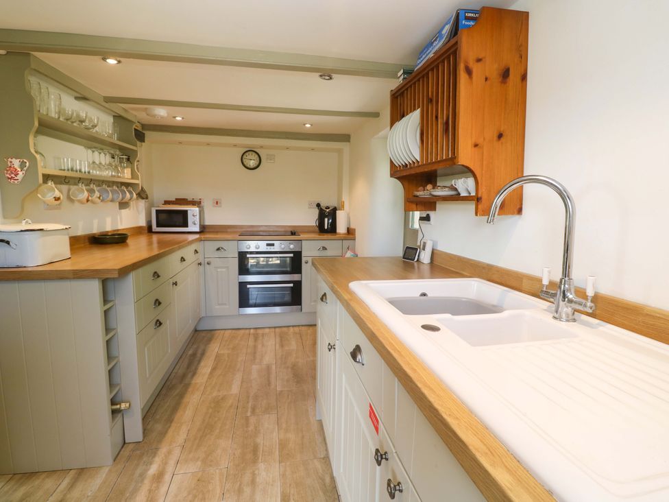 A kitchen with countertop, sink, oven, and microwave at Greenways in Perranporth