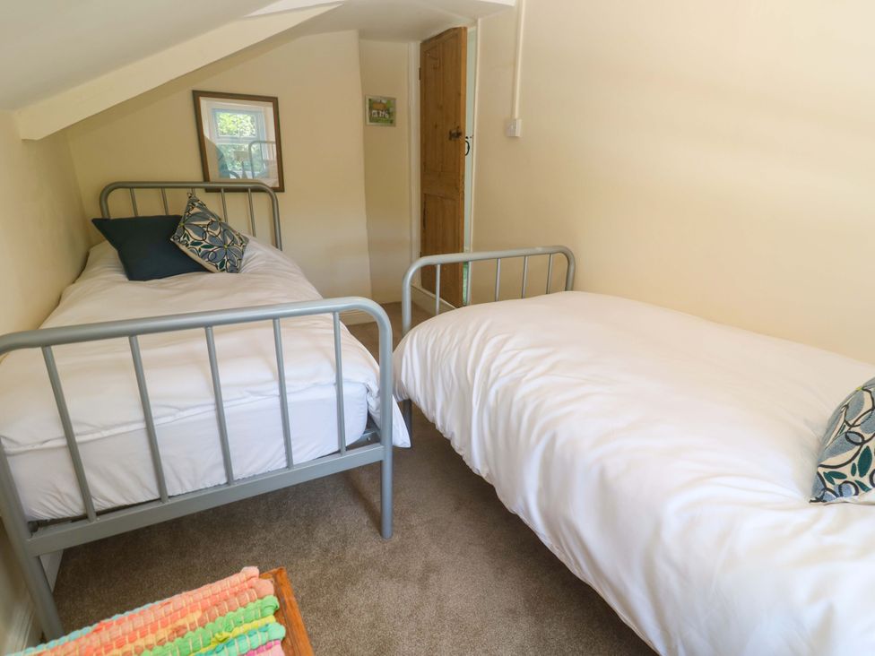 A bedroom with two single beds and a mirror at Greenways in Perranporth