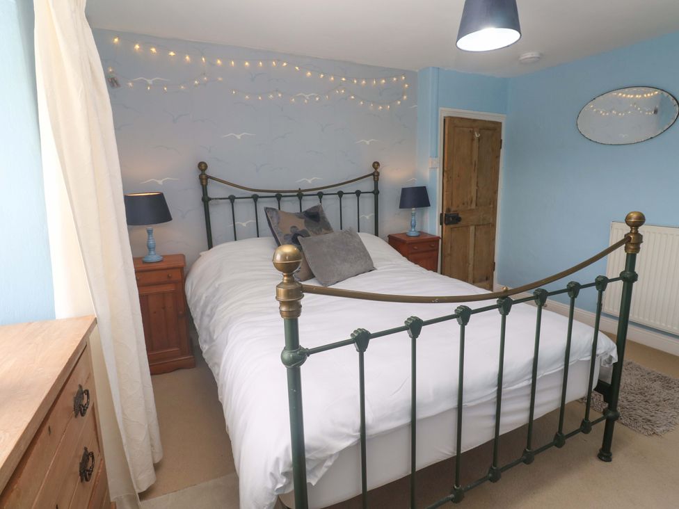 A bedroom with a bed and nightstands at Greenways in Perranporth