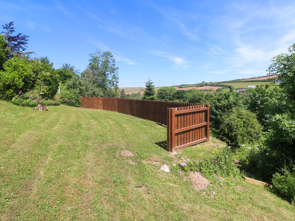 A garden with a wooden fence and trees at Greenways in Perranporth