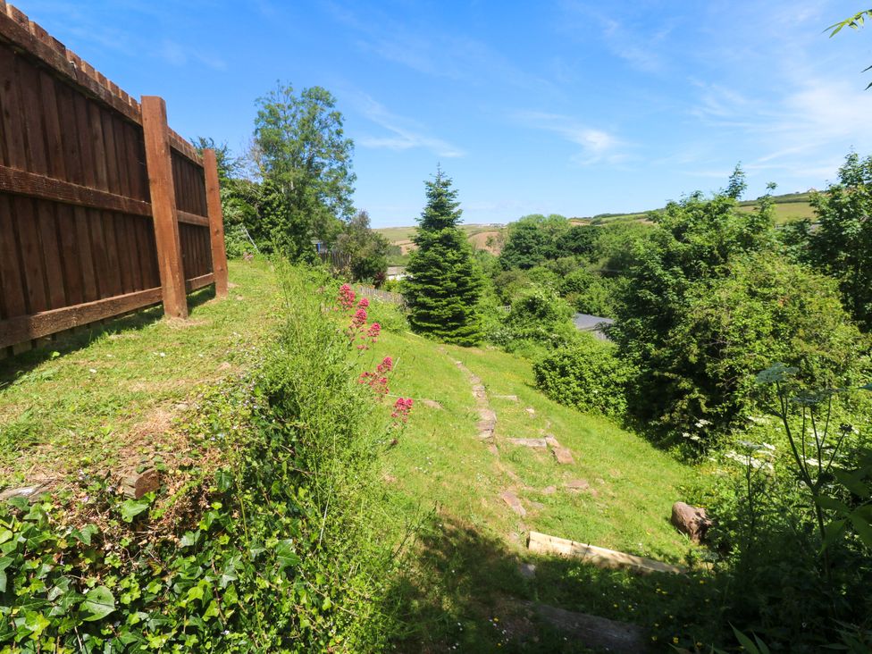 A garden with a fence, grass, flower, tree and path at Greenways in Perranporth