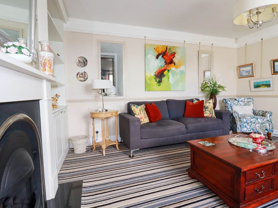 A living room with a gray sofa and colorful cushions a wooden coffee table and a patterned armchair at Cathedral View Cottage in Truro