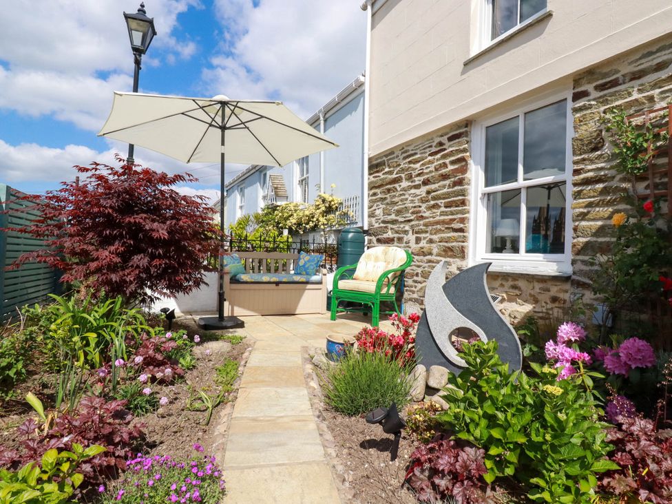 A garden patio with plants and flowers seating area and umbrella at Cathedral View Cottage in Truro
