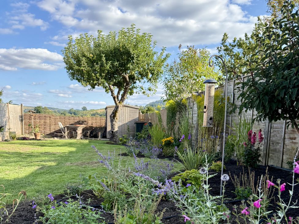 A garden with a tree and a bird feeder at The Garden Retreat in Winchcombe