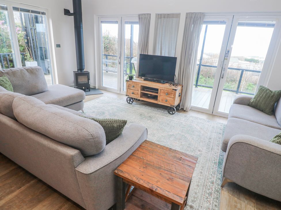 A living room with a sofa, television, and wood stove at Bay View in Portreath