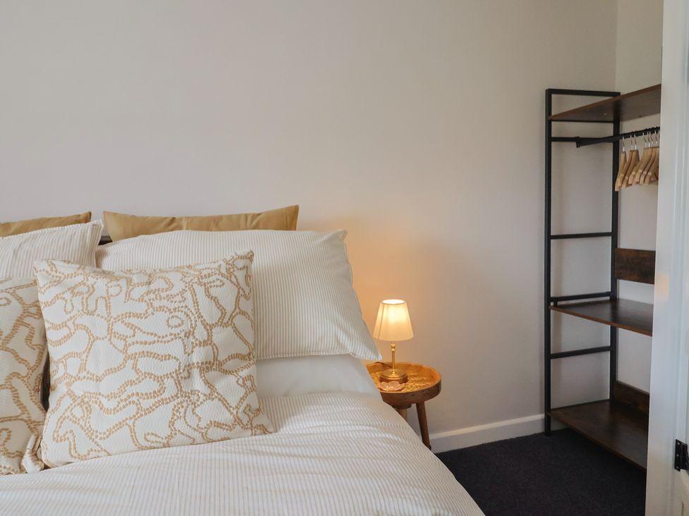 A bedroom with a bed and a clothes rack at 6 Bedford Place in Bridport