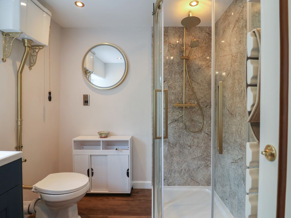 A bathroom featuring a toilet, sink, shower, and mirror at 6 Bedford Place in Bridport