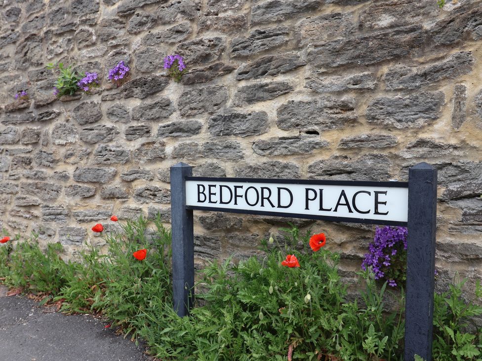A street sign with the name Bedford Place beside a stone wall in Bridport