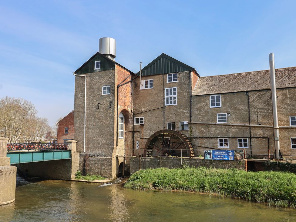 A building with a water wheel next to a bridge in Bridport at 6 Bedford Place