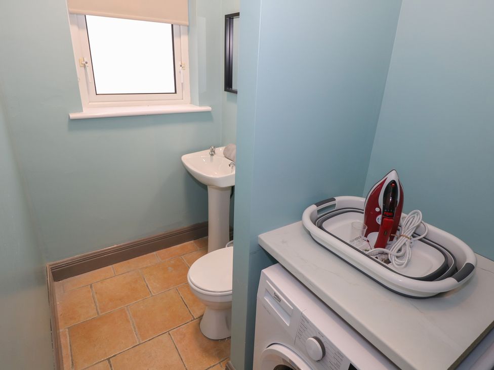 A bathroom with a sink, toilet, washing machine and iron at No.3 Beach Cottages Keel, County Mayo