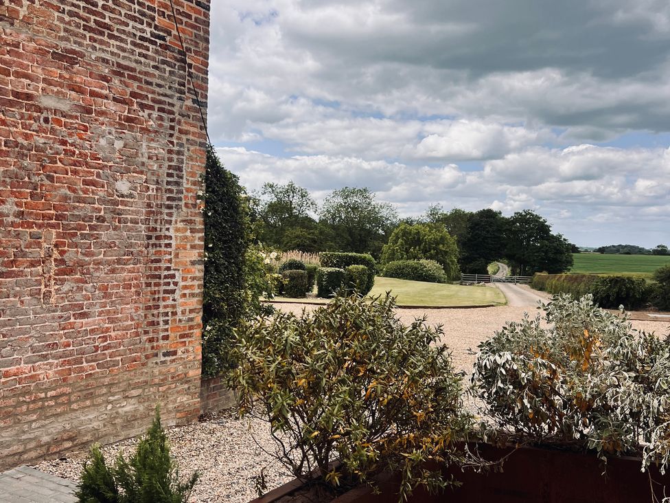A garden view with a brick wall and drive at Wabi in Gembling near Beeford