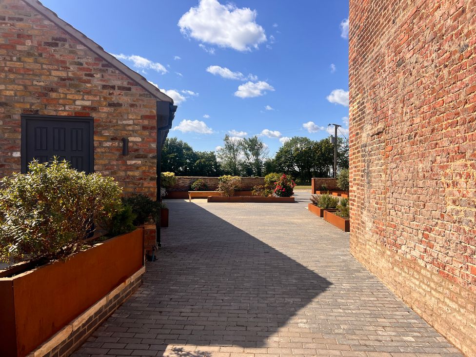 An outdoor area with a brick wall and planters at Wabi in Gembling near Beeford