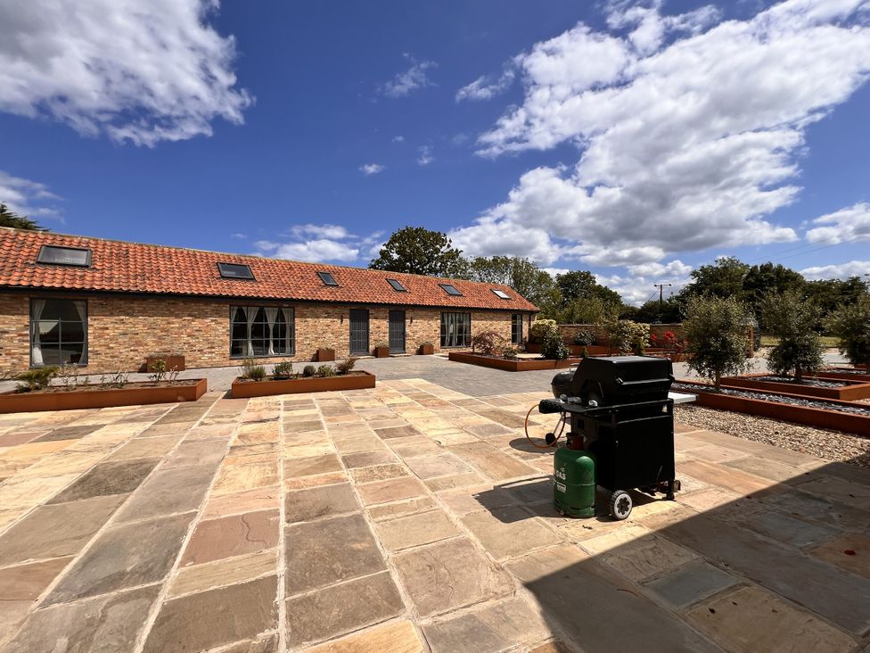 An outdoor area with a building, grill, and flower beds at Sabi Gembling near Beeford