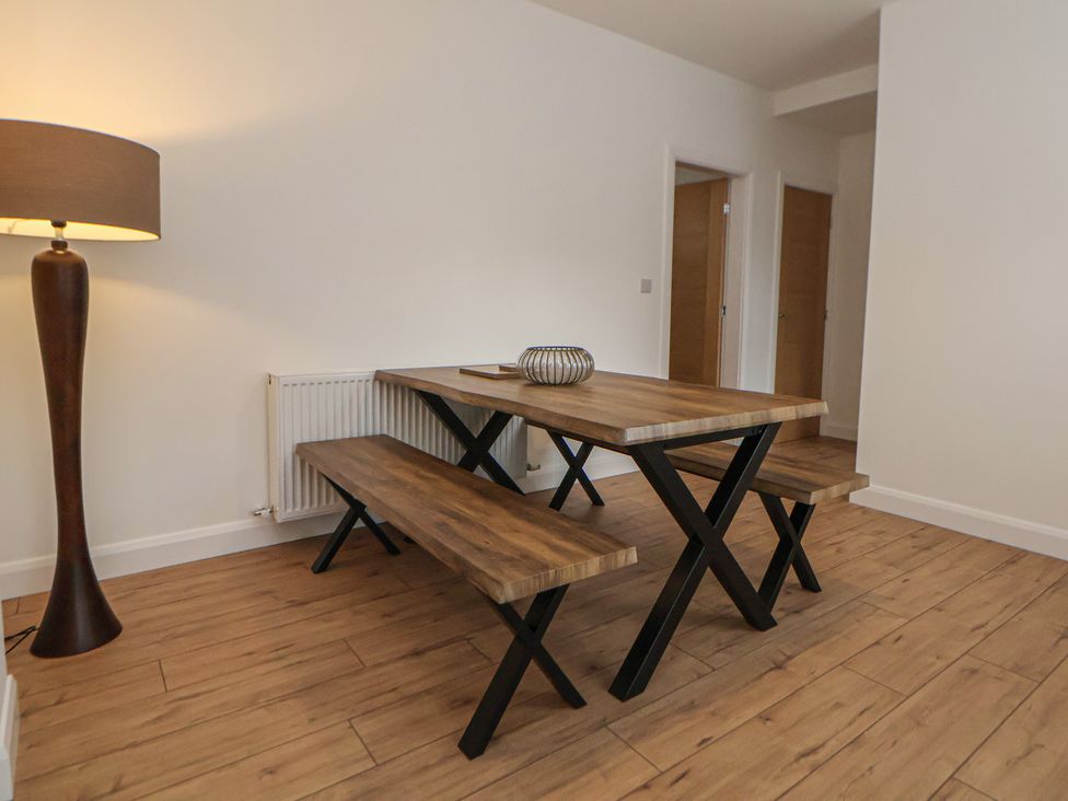 A dining room with a wooden table and benches at 5 Marsh Lane in Flint