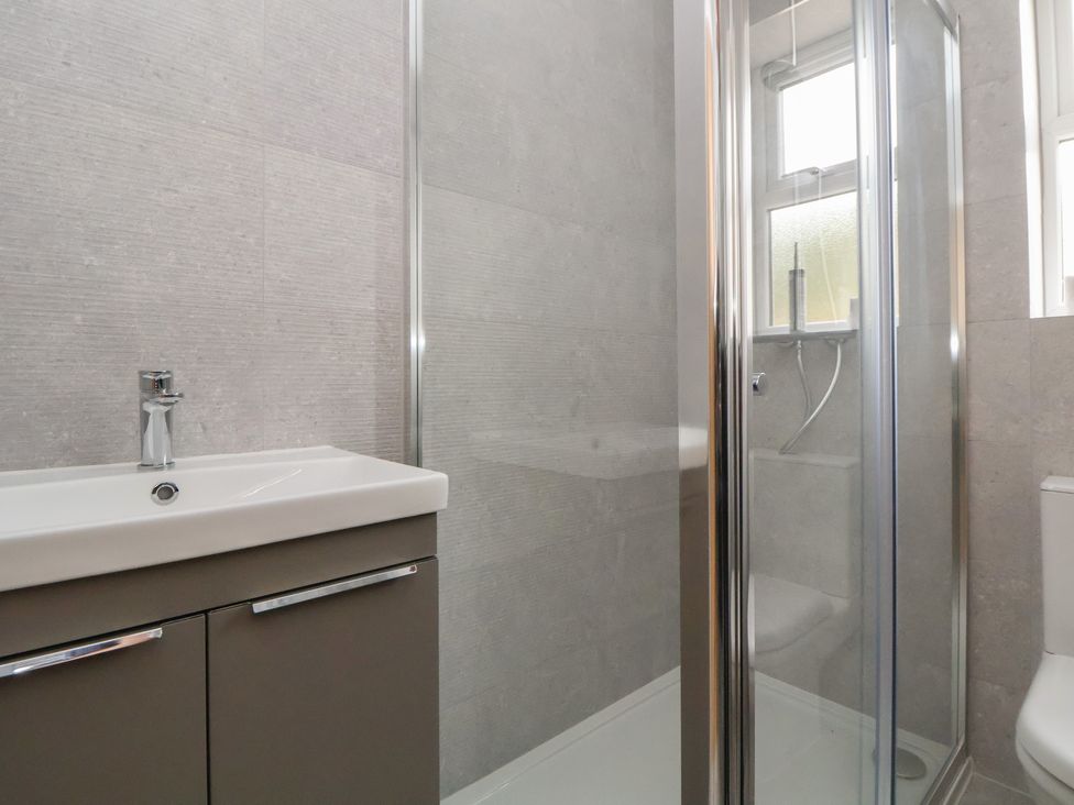 A bathroom with a sink, shower, and toilet at 5 Marsh Lane in Flint